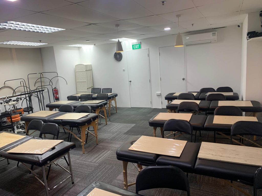 The practical room at the NAYUMI studio: rows of treatment beds, chairs and work lamps